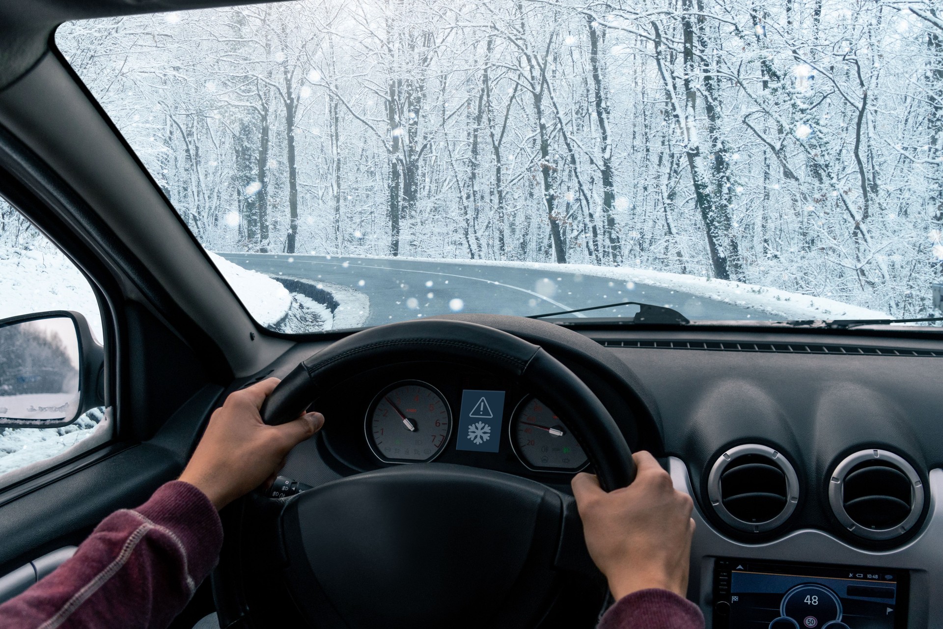 A man is driving a car on a winter road